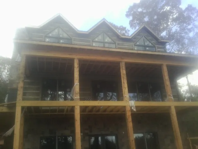 Dormers and porch framing on a large log home under construction — Roof Coating work by our crew in Glencoe