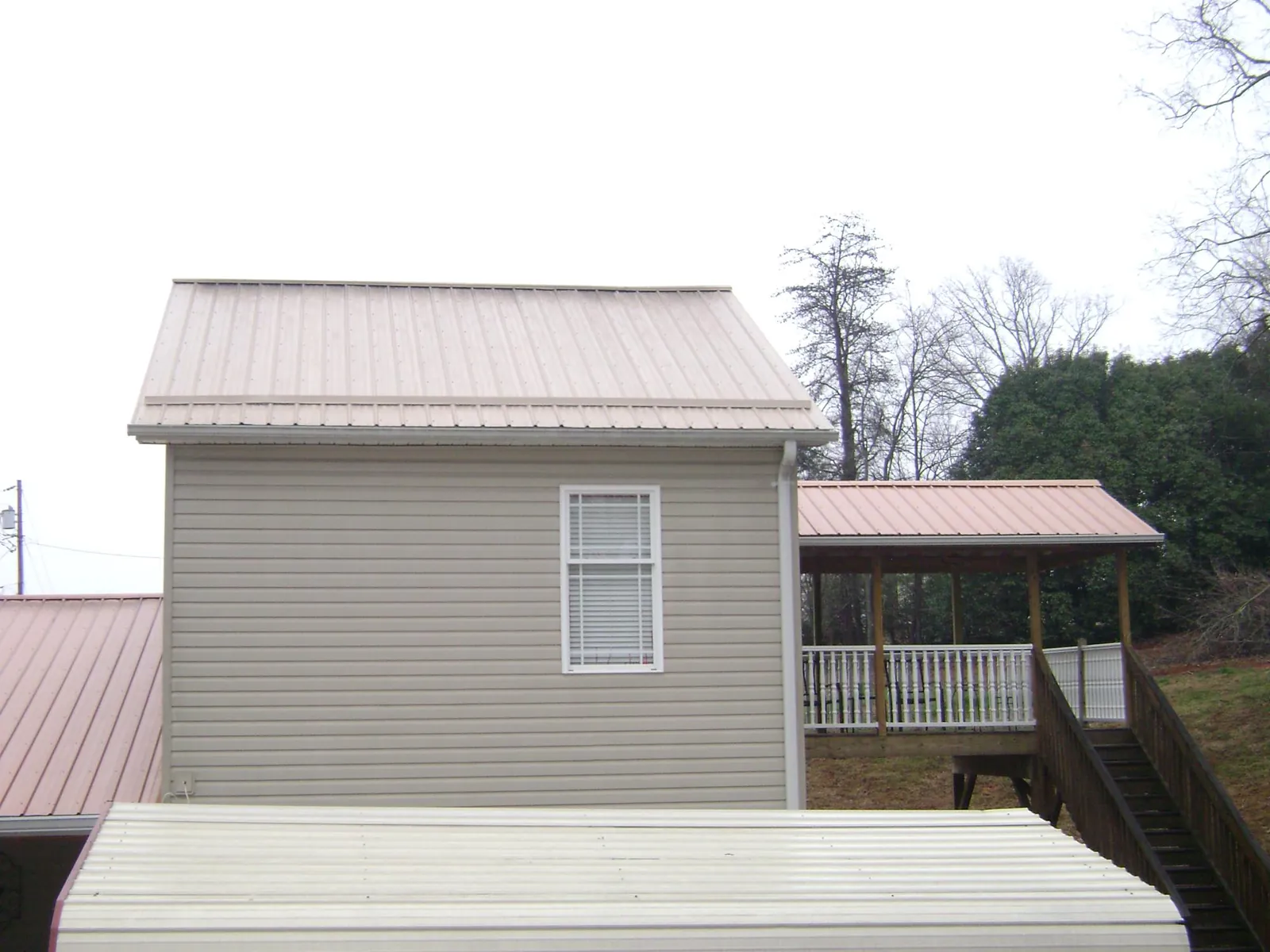 Tan metal roofs on a two story addition and attached porch, from a Roof Replacement job in Glencoe